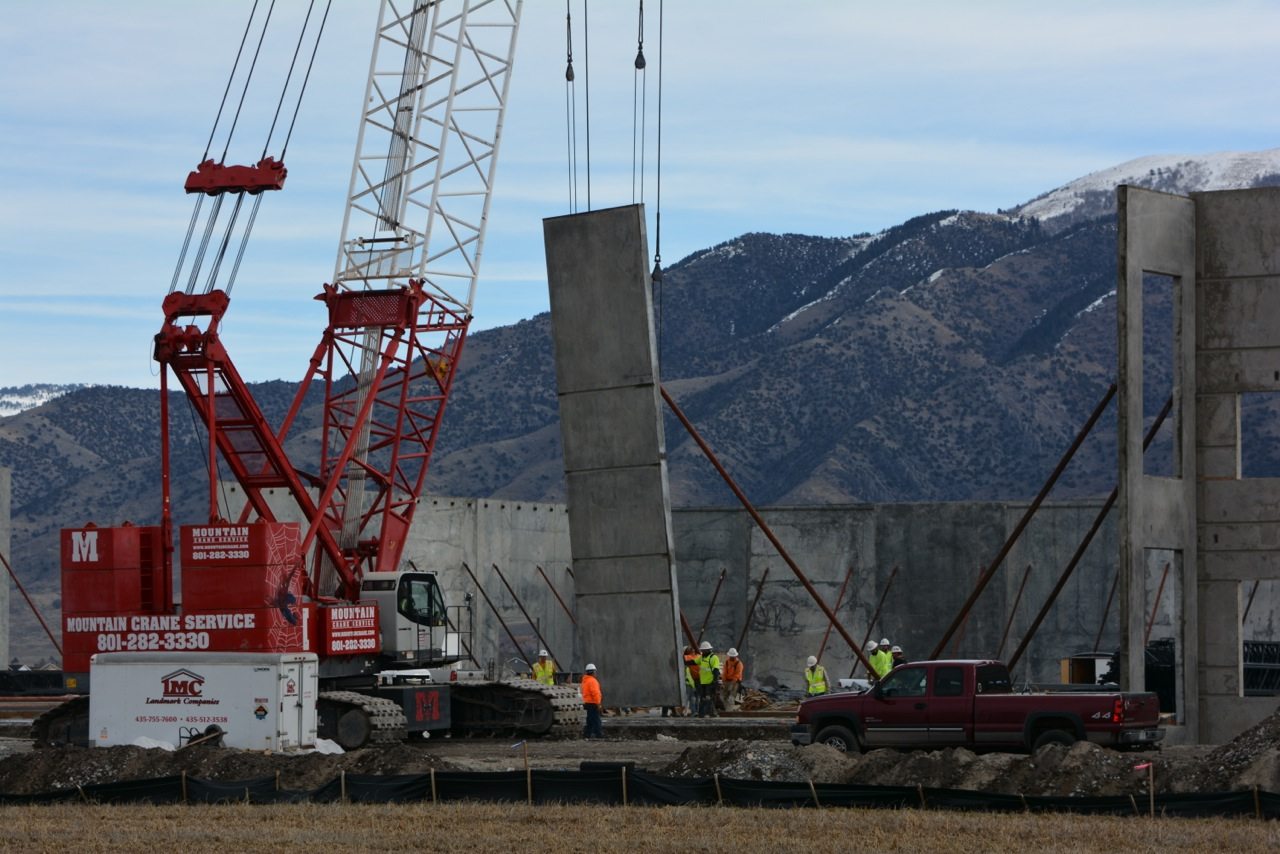 A crane lifts a concrete panel